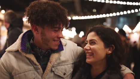 Portrait-Of-Young-Couple-Enjoying-Christmas-Market-At-Night