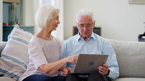 Älteres-Paar-Sitzt-Zusammen-Auf-Dem-Sofa-Und-Benutzt-Laptop-Zu-Hause