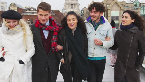 Group-Of-Young-Friends-Walking-Over-Millennium-Bridge-In-London