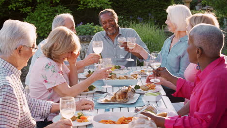 Group-Of-Senior-Friends-Enjoying-Outdoor-Dinner-Party-At-Home