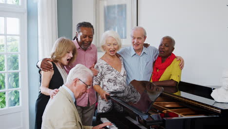 Gruppe-Von-Senioren,-Die-Am-Klavier-Stehen-Und-Gemeinsam-Singen