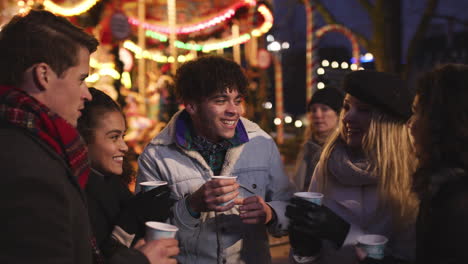 Group-Of-Friends-Drinking-Mulled-Wine-At-Christmas-Market