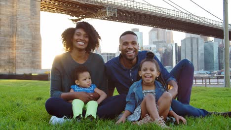 Young-black-family-sitting-by-bridge-in-Manhattan,-New-York