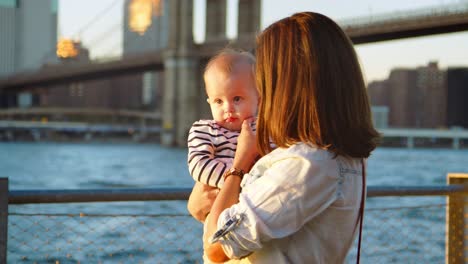 Young-mother-with-daughter-standing-by-bridge,-Manhattan