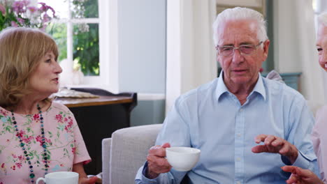 Group-Of-Senior-Friends-Enjoying-Cup-Of-Tea-At-Home-Together