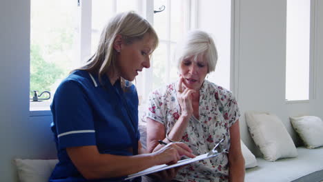 Nurse-sits-doing-a-questionnaire-with-a-senior-woman