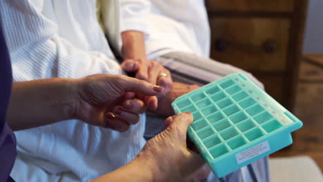 Close-Up-Of-Nurse-Helping-Senior-Woman-With-Medication-At-Home