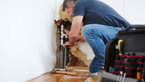 Domestic-Plumber-With-Tools-Repairing-Leaking-Pipe