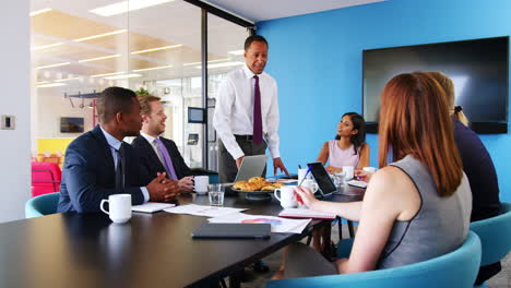 Black-male-manager-stands-talking-at-a-business-meeting