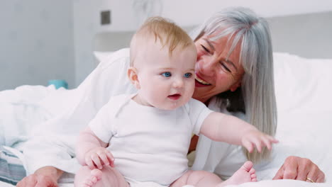 Grandmother-Lying-In-Bed-At-Home-Looking-After-Baby-Grandson
