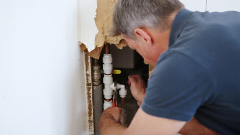 Close-Up-Of-Domestic-Plumber-With-Tools-Repairing-Leaking-Pipe