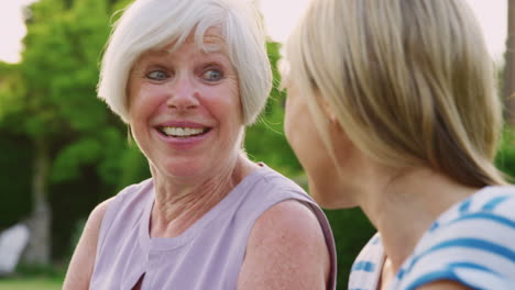 Happy-senior-woman-and-adult-daughter-talking-in-garden