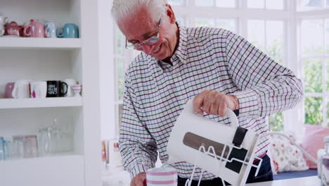 Senior-man-making-tea-in-the-kitchen-using-kettle-tipper