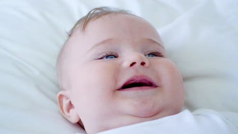 Overhead-Shot-Of-Baby-Boy-Lying-On-Bed-And-Smiling