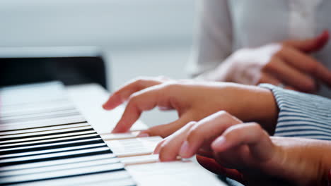Close-Up-Of-Pupil-With-Teacher-Playing-Piano-In-Music-Lesson