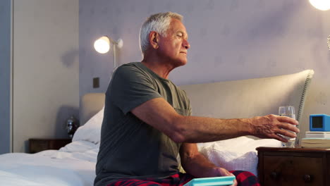 Älterer-Mann-Sitzt-Zu-Hause-Im-Bett-Und-Nimmt-Medikamente