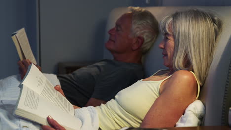 Senior-Couple-Wearing-Pajamas-Lying-In-Bed-Reading