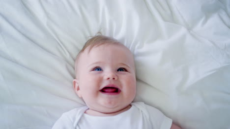 Overhead-Shot-Of-Baby-Boy-Lying-On-Bed-And-Laughing