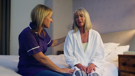 Enfermera-Hablando-Con-Una-Mujer-Mayor-En-El-Dormitorio-Durante-Una-Visita-Domiciliaria