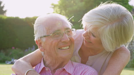 Happy-senior-couple-embrace-and-smile-to-camera-in-garden