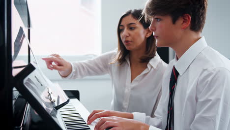 Männlicher-Schüler-Mit-Lehrer,-Der-Im-Musikunterricht-Klavier-Spielt