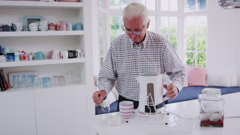 Senior-man-making-tea-in-the-kitchen-using-kettle-tipper