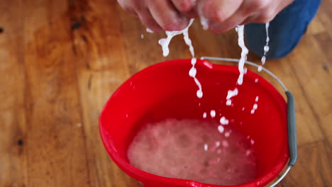 Close-Up-Of-Man-Squeezing-Water-Into-Bucket-After-Domestic-Leak