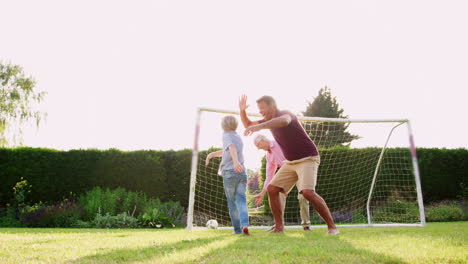 Three-male-generations-of-a-family-playing-soccer-in-garden