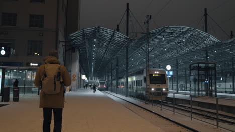 Train-leaving-the-station-at-night-and-man-making-video-on-mobile