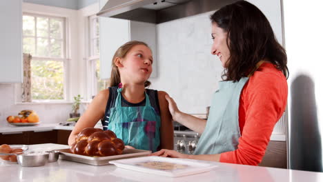 Mother-and-daughter-smell-freshly-baked-challah-in-kitchen