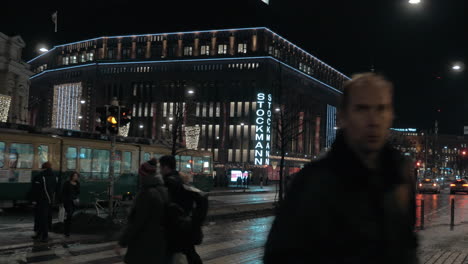 Calle-Con-Tranvía-Del-Centro-Comercial-Stockmann-Y-Tráfico-De-Personas-En-Helsinki-Por-La-Noche