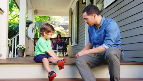Father-And-Son-Sit-On-Porch-Of-House-Playing-With-Toys-Together