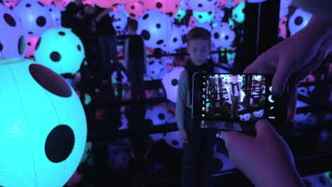 Taking-photo-of-child-in-Infinity-Mirror-room-with-dotted-balls-by-Yayoi-Kusama