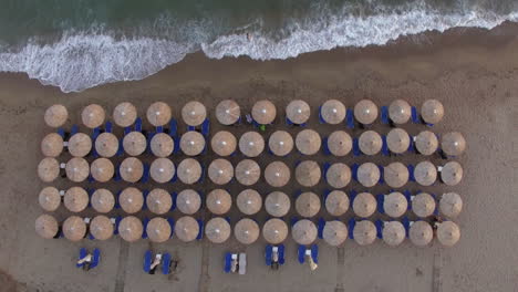 Sunbeds-at-the-beach-with-few-people-relaxing-there-aerial-view
