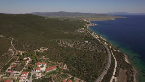 Küste-Mit-Hütten-Und-Grünen-Hügeln,-Luftaufnahme-Des-Strandes-Von-Trikorfo,-Griechenland