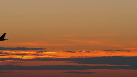 Airplane-black-silhouette-flying-against-golden-evening-sky