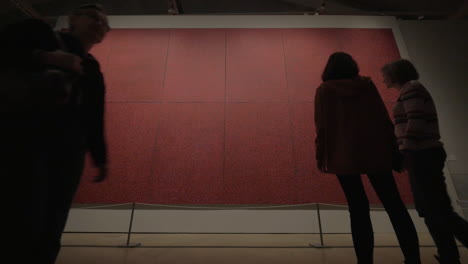 Art-museum-visitors-looking-at-red-polka-painting-by-Yayoi-Kusama
