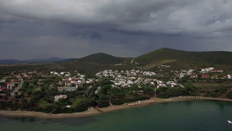 Flying-over-sea-beach-and-cottages-in-resort-town-of-Greece-on-overcast-day