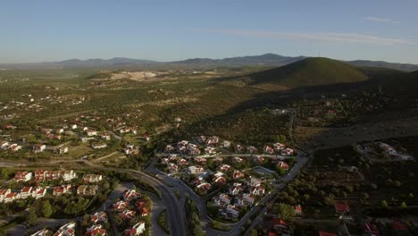 Flying-over-the-town-and-green-landscape-with-hills-Trikorfo-Beach-Greece