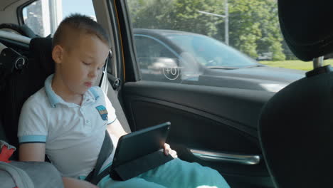 Gelangweiltes-Kind,-Das-Während-Der-Autofahrt-Einen-Film-Auf-Dem-Pad-Anschaut
