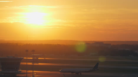 Blick-Auf-Den-Flughafen-Mit-Fahrendem-Flugzeug-Bei-Goldenem-Sonnenuntergang