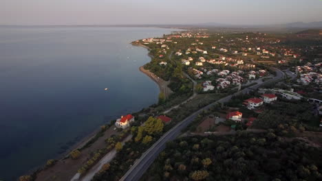Flying-over-Trikorfo-Beach-coastline-with-cottages-and-green-uplands-Greece
