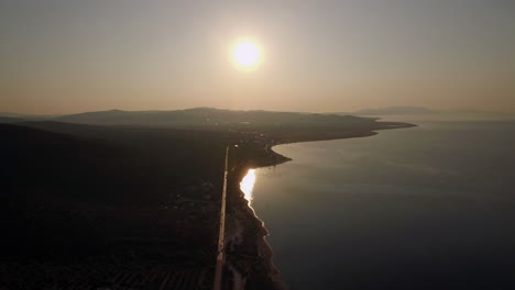 Aerial-scene-of-shoreline-and-green-upland-at-sunset-Greece