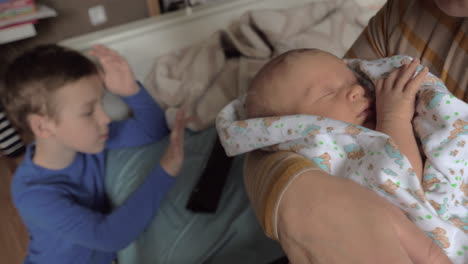 Grandma-with-grandchildren-at-home-She-rocking-baby-granddaughter-in-arms