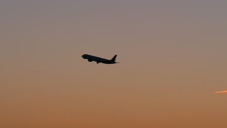 Schwarze-Silhouette-Eines-Flugzeugs,-Das-Am-Abendhimmel-Fliegt