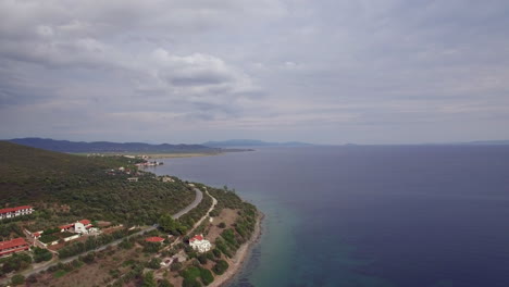 Luftaufnahme-Der-Meeresküste-Mit-Grünen-Hügeln-Und-Häusern-Am-Strand-Von-Trikorfo,-Griechenland