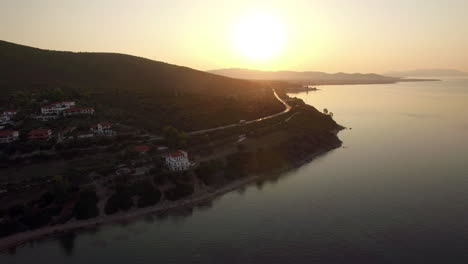 Flying-over-sea-and-Trikorfo-Beach-coastline-at-sunset-Greece