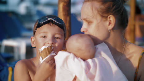 Mother-with-baby-and-elder-son-at-the-beach-Boy-eating-ice-cream