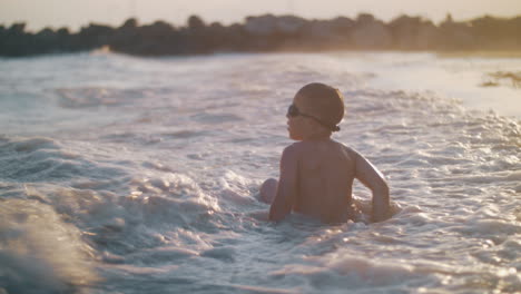 Child-bathing-in-the-sea-near-shore-at-sunset