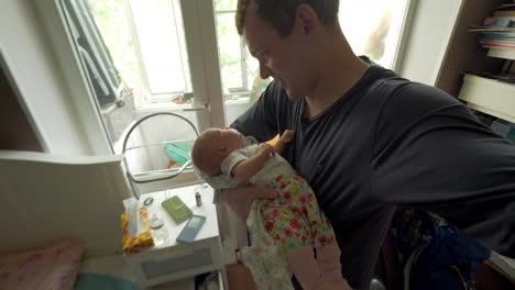 Dad-lulling-baby-daughter-at-home